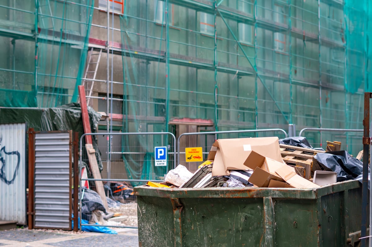 A green skip filled with waste at a construction site